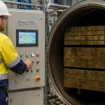 Worker monitoring wood treatment equipment in a commercial lumber processing facility