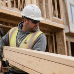 Construction worker handling lumber during custom residential home construction